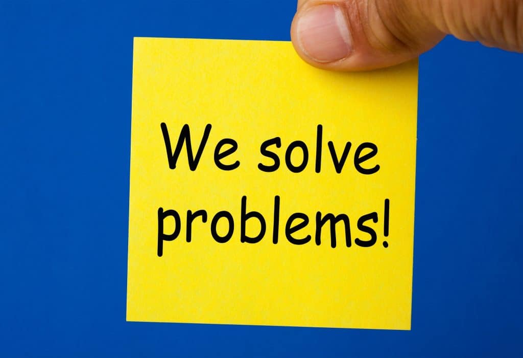 Hand holding yellow sticky note written we solve problems. Business concept.