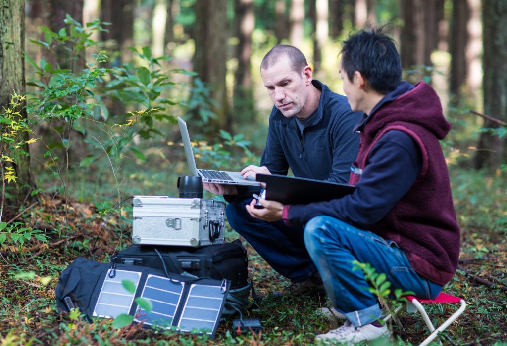 Two environmentalists or scientists monitor the forest with a solar powered field laboratory